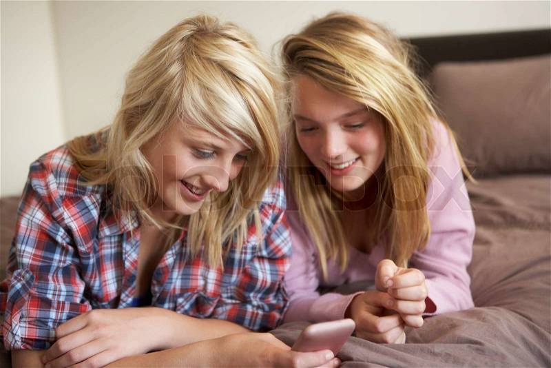 Two Teenage Girls Lying On Bed Looking At Pregnancy Testing Kit, stock photo