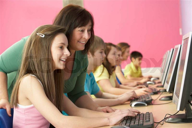 Teenage Students In IT Class Using Computers In Classroom With Tutor, stock photo