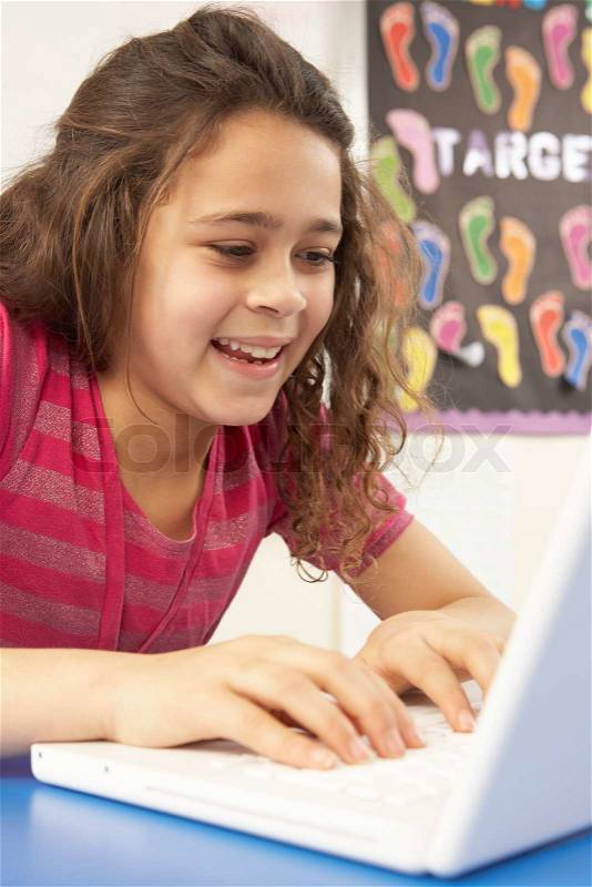 Schoolgirl In IT Class Using Computer With Teacher, stock photo