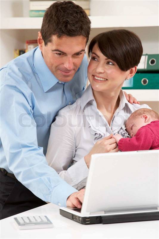 Parents With Newborn Baby Working From Home Using Laptop, stock photo
