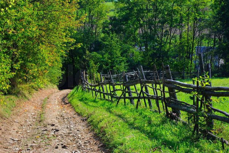 Rural landscape with road and wooden fence, stock photo