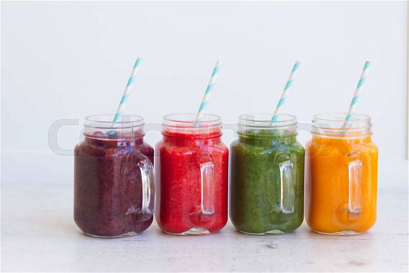 Colorful smoothy drinks in glass jars on white table, stock photo