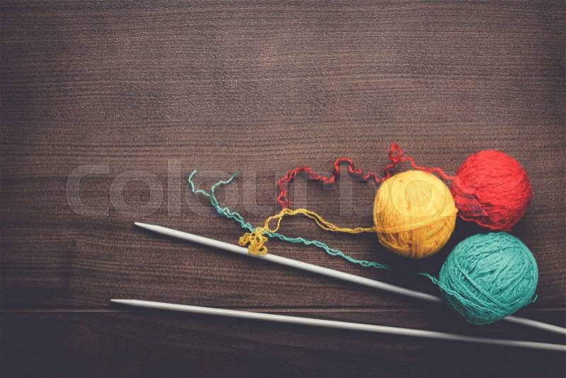 Knitting needles and colorful ball of threads on wooden background, stock photo