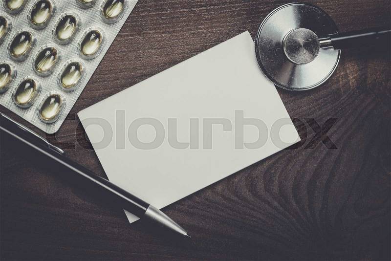 Blank notebook statoscope and pills on the dark brown wooden table, stock photo