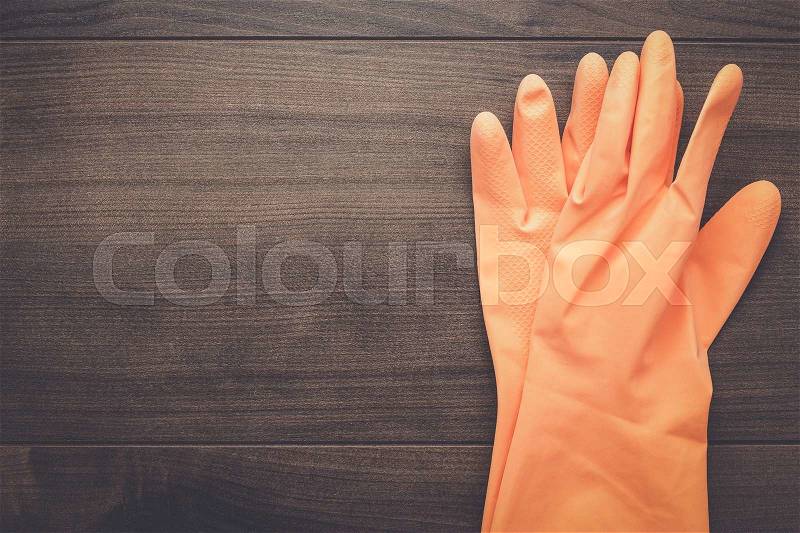 Orange rubber cleaning gloves on wooden background, stock photo