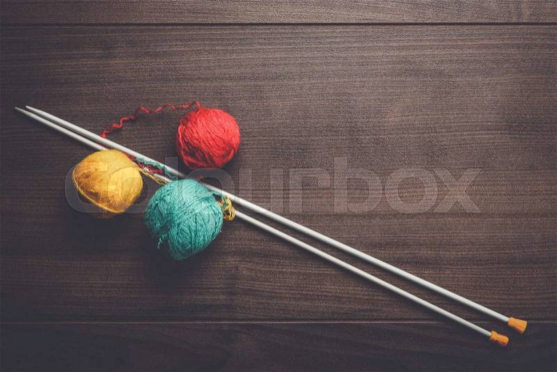 Knitting needles and colorful ball of threads on the wooden background, stock photo