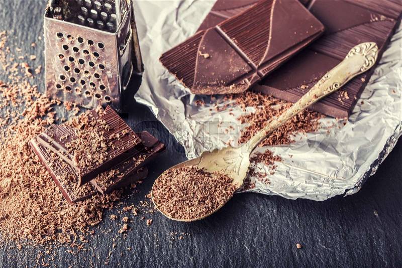 Chocolate. Black chocolate. A few cubes of black chocolate. Chocolate slabs spilled from grated chockolate powder, stock photo