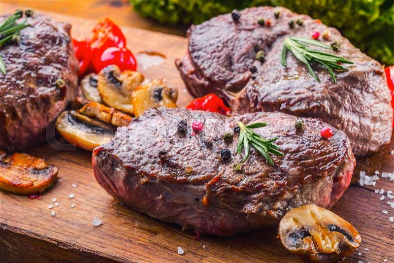 Grill beef steak. Portions thick beef juicy sirloin steaks on grill teflon pan or old wooden board, stock photo