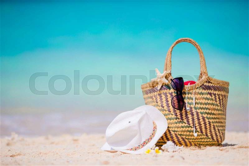 Beach accessories - straw bag, white hat, starfish and black sunglasses on the beach. Summer beach concept, stock photo