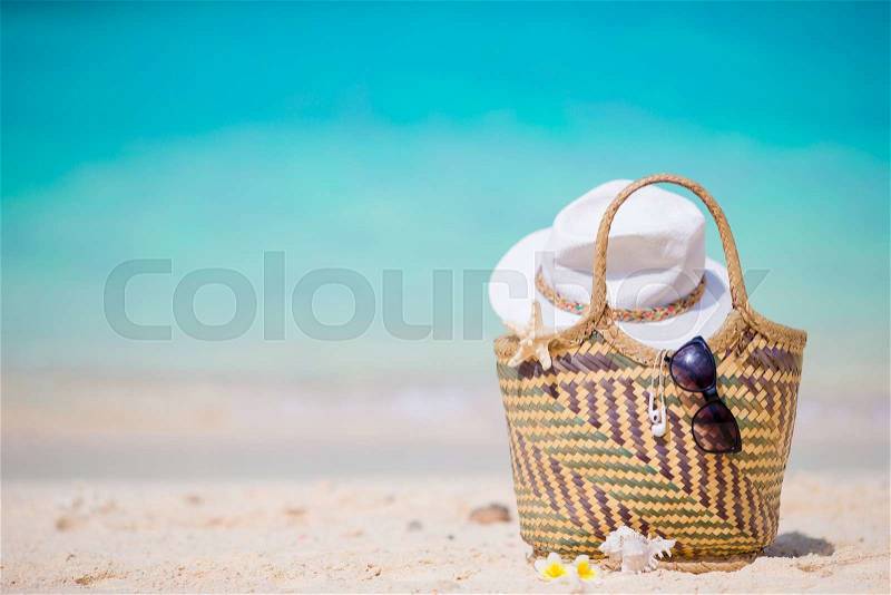 Beach accessories - straw bag, white hat and black sunglasses on the beach, stock photo
