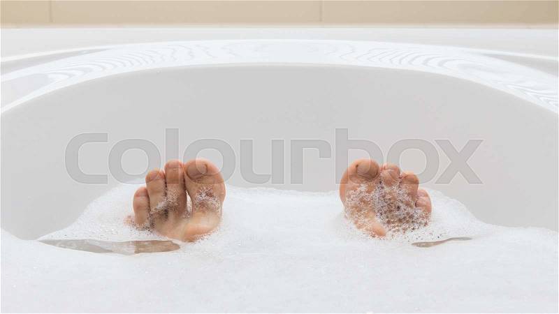 Men\'s feet in a bright white bathtub, selective focus on toes, stock photo