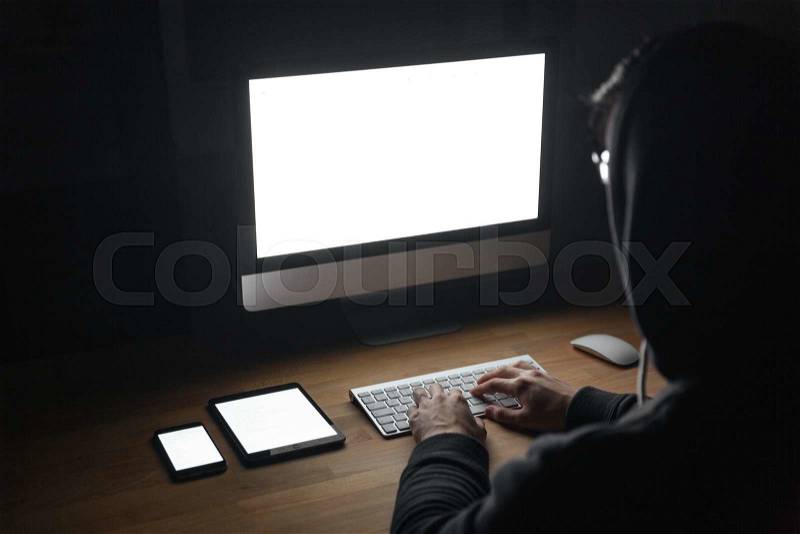 Back view of hacker using blank screen computer, tablet and smartphone, stock photo