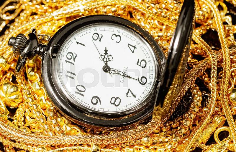 Pocket watch with pile of various golden jewelry, isolated black background, stock photo