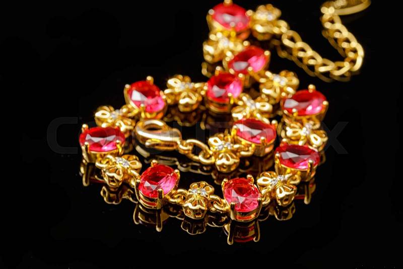 Ruby gold bracelet isolated on black background, stock photo