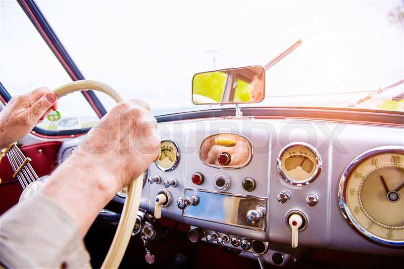 Close up unrecognizable man driving a veteran car, hands on steering wheel, stock photo