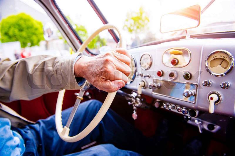 Close up unrecognizable man driving a veteran car, hands on steering wheel, stock photo