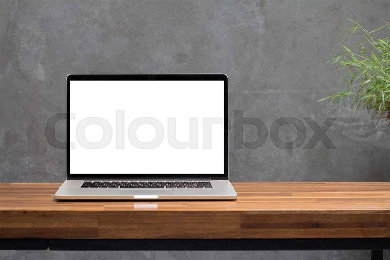 Laptop blank screen on wooden table with concrete wall background, stock photo