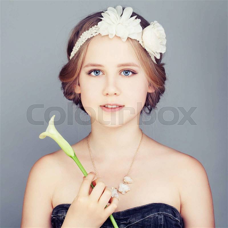 Young Girl holding Lily Flower. Cute Face and Bohemian Boho Chic Hairstyle, stock photo