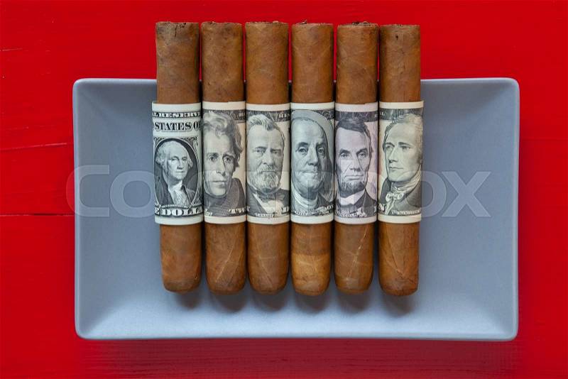 Gray ceramic dish and luxury Cuban cigars with US dollar banknotes on over red background, rectangle dish, stock photo