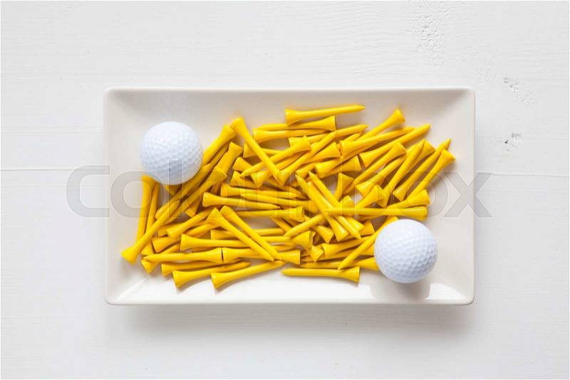 White ceramic dishes with golf balls and wooden tees on over white background, rectangle dish, stock photo