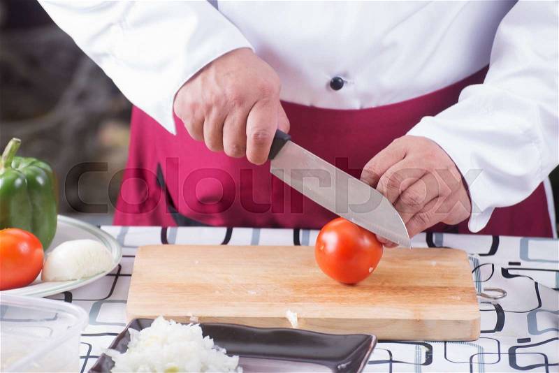Chef cutting Tomato with knife befoer cooking / cooking spaghetti concept, stock photo