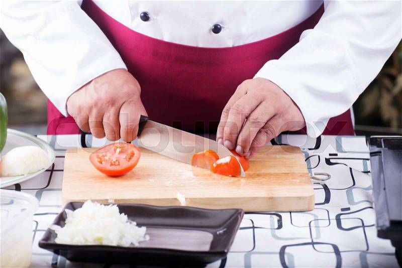 Chef cutting Tomato with knife before cooking / cooking spaghetti concept, stock photo