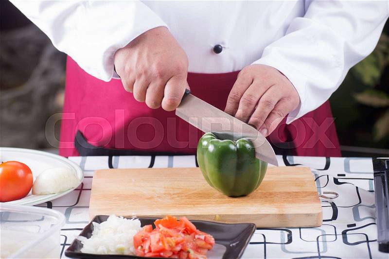 Chef cutting green bell pepper with knife before cooking / cooking spaghetti concept, stock photo