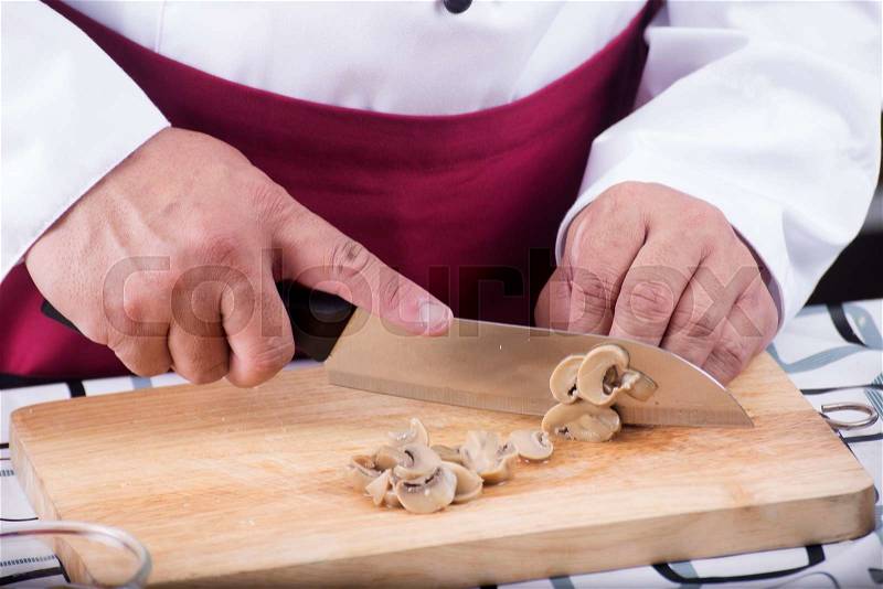 Chef cutting mushroom with knife before cooking / cooking spaghetti concept, stock photo