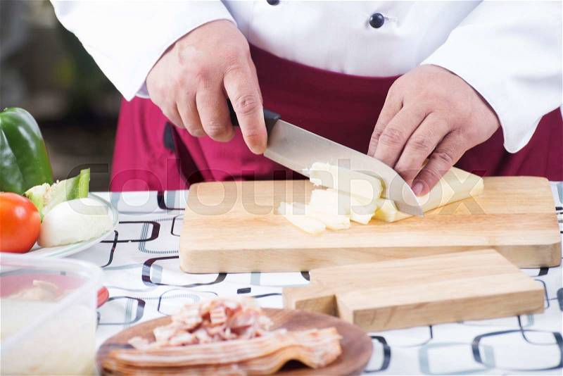 Chef cutting cheese with knife before cooking / cooking spaghetti concept, stock photo