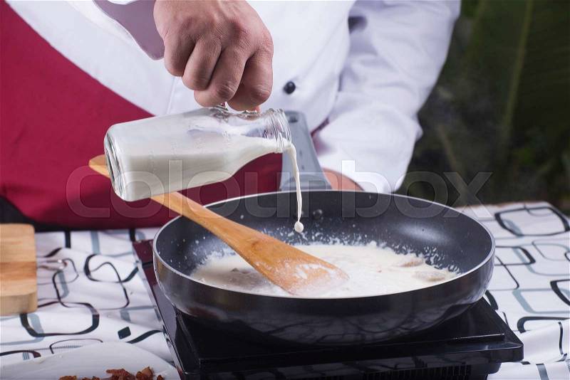 Chef pouring fresh milk to the pan / cooking spaghetti concept , stock photo