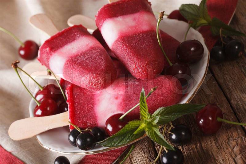 Fruit ice cream with cherry and currants on a stick closeup on a plate. Horizontal , stock photo