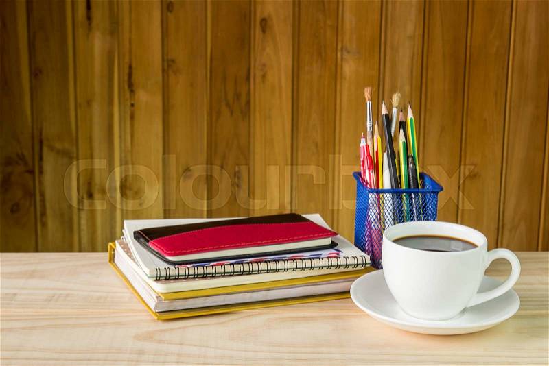 Note book,coffee cup,and stack of book on wooden table background, stock photo