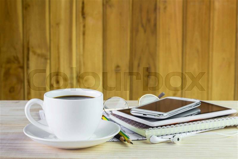 Note book,smart phone,coffee cup,and stack of book on wooden table background, stock photo