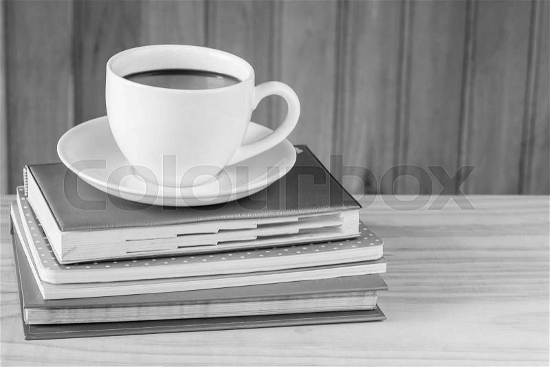 Cup of coffee and note book on wooden table background.black and white tone, stock photo