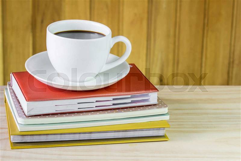 Cup of coffee and note book on wooden table background, stock photo