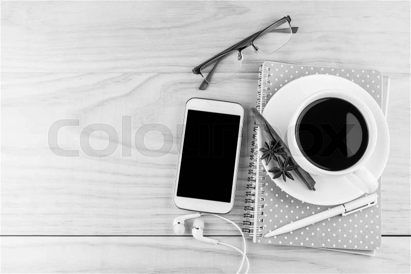 Smart phone, coffee,glasses and book with white pen on wood table background. business concept.black and white tone, stock photo