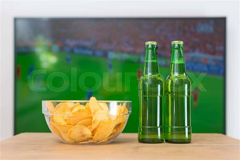 Beer and chips in front of TV with football match, stock photo