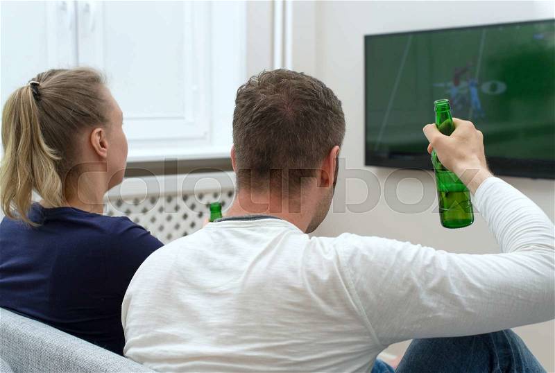 Couple watching American football on tv, stock photo