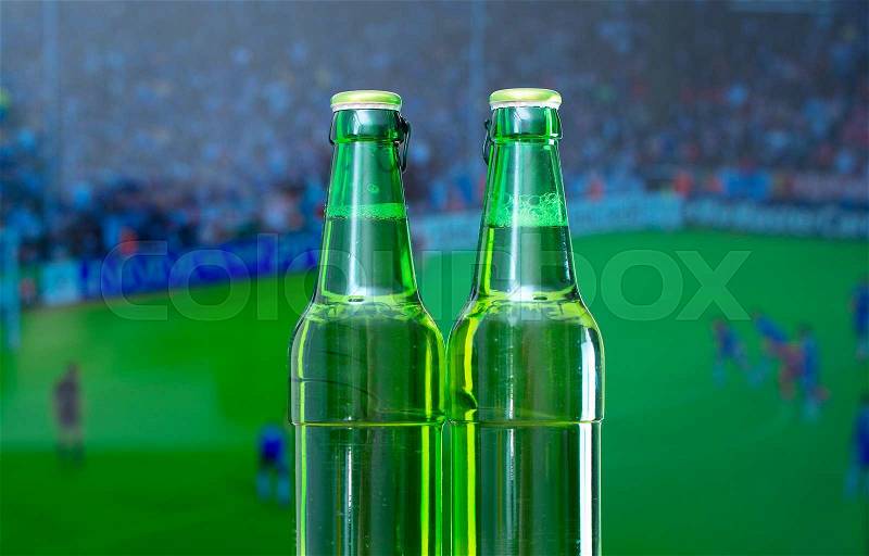 Two bottles of beer in front of TV with football match, stock photo
