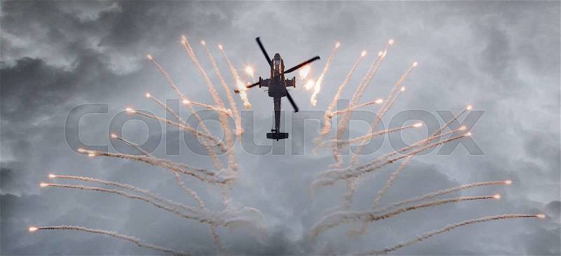Silhouette of an attack helicopter firing flares, storm is coming, stock photo