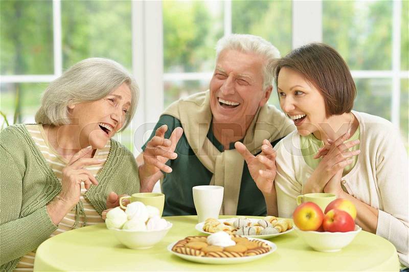 Cute family portrait , adult daughter with senior parents drinkig tea, stock photo