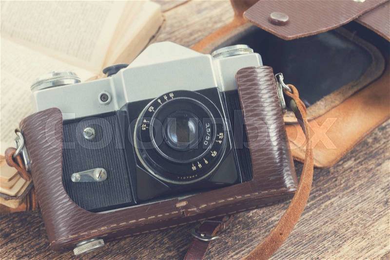 Retro photo camera with books on wooden shelf, retro toned, stock photo