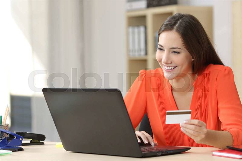 Entrepreneur buying online with a credit card and a laptop in a desk at home or a little office, stock photo