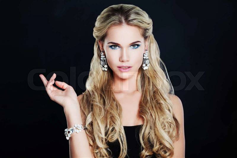Gorgeous Woman with Makeup, Blonde Curly Hairstyle and Jewelry on Black Background, stock photo