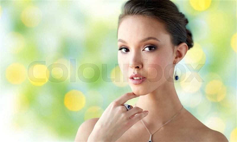 Beauty, jewelry, people and luxury concept - beautiful asian woman or bride with earring, finger ring and pendant over summer green lights background, stock photo
