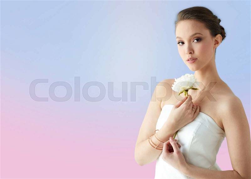 Beauty, jewelry, people and luxury concept - beautiful asian woman or bride in white dress with peony flower, golden ring and bracelet over rose quartz and serenity gradient background, stock photo