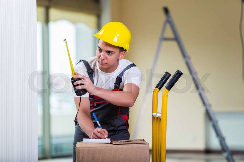 Delivery man taking dimensions with tape measure, stock photo