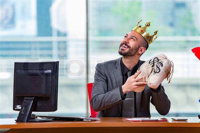 Businessman with crown and money sacks in the office, stock photo