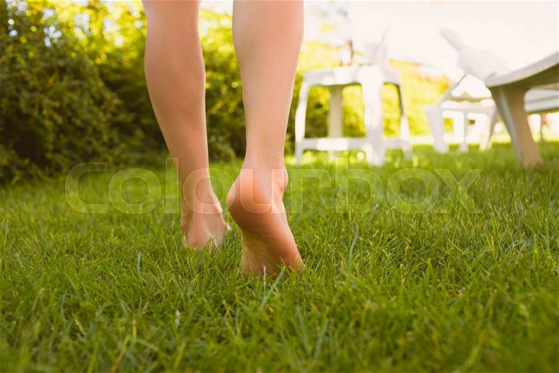 Close up female crossed legs walking on the grass in a park, stock photo