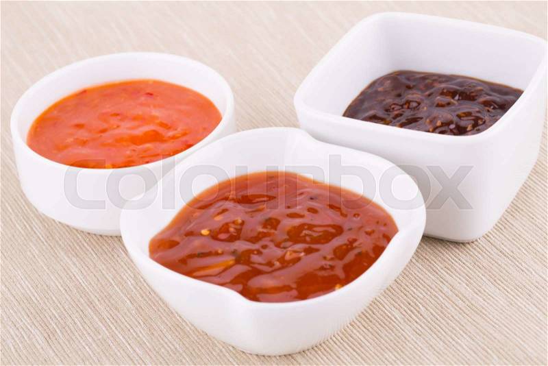 Different sauces in saucers on beige cloth background, stock photo